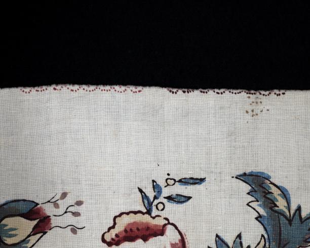 Detail van de rand van de Koningssprei in de colletcie van Museum Rotterdam. Er is nog een fractie van de initialen van de drukkers zichtbaar.