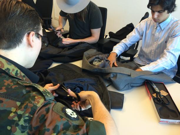 Studenten knippen en scheuren de tweedehands colberts die zijn meegebracht door Adam voor nader onderzoek.