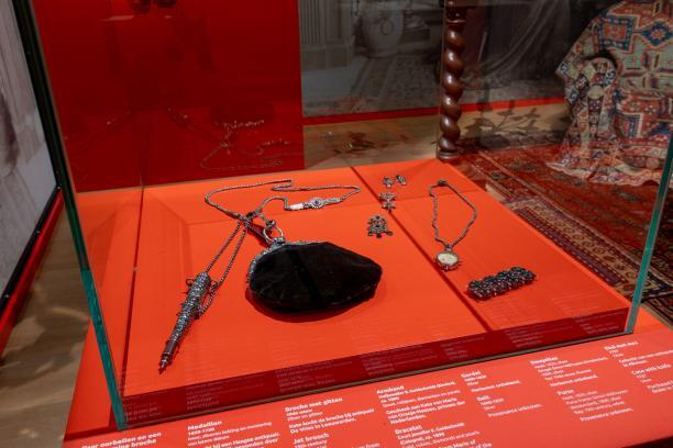 Beugeltas en sieraden die Kate draagt op de header-afbeelding.