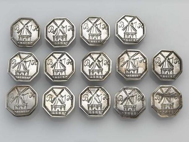 Veertien achtkantige zilveren knopen, op de voorzijde een molen gegraveerd, aan weerskanten van de wieken de letters B.H. Fries museum T1955-0682