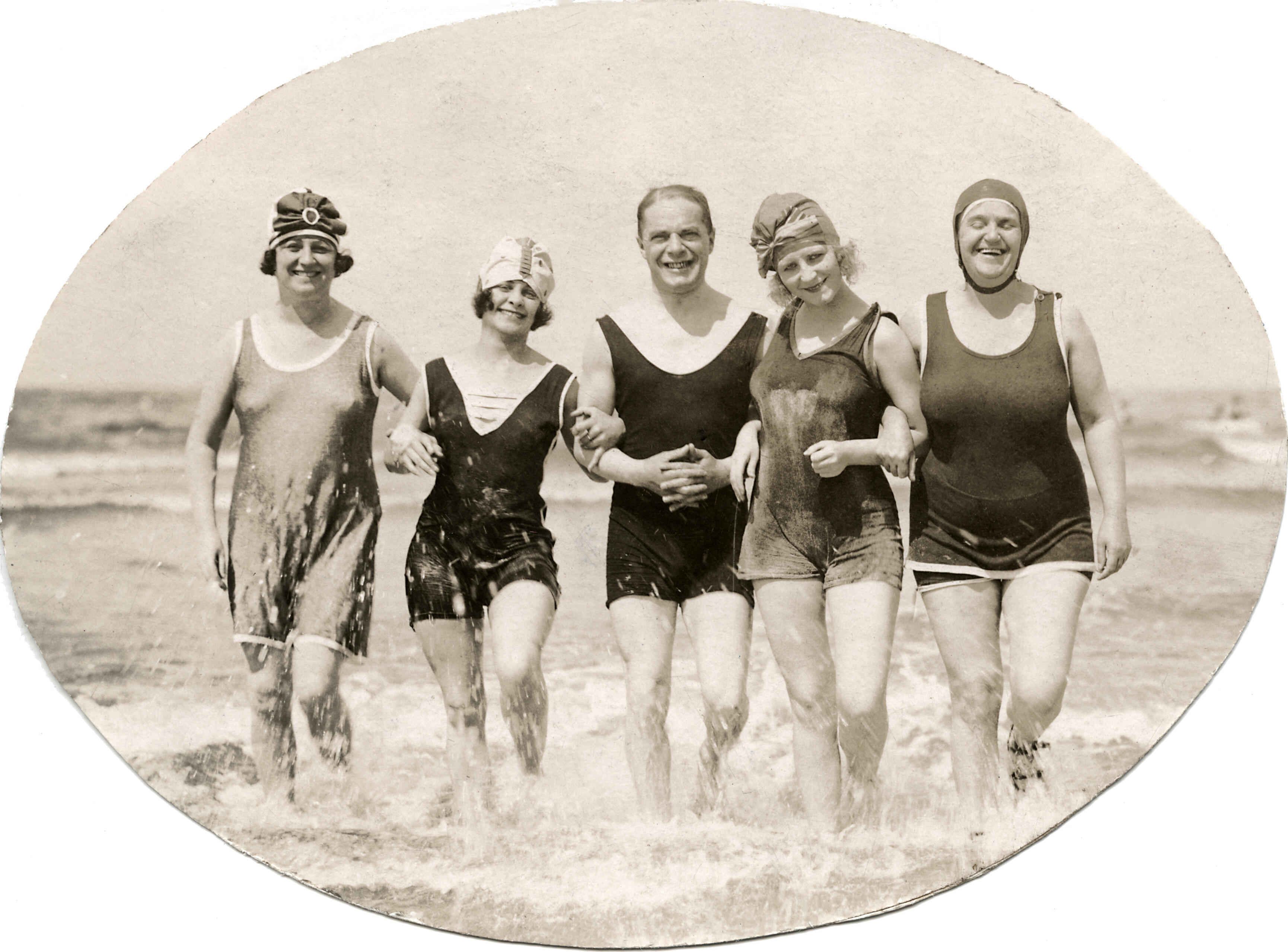 Badpakken. Een man tussen vier vrouwen, in badpak, rennend door de branding.Plaats en land onbekend. Badnummer 1923