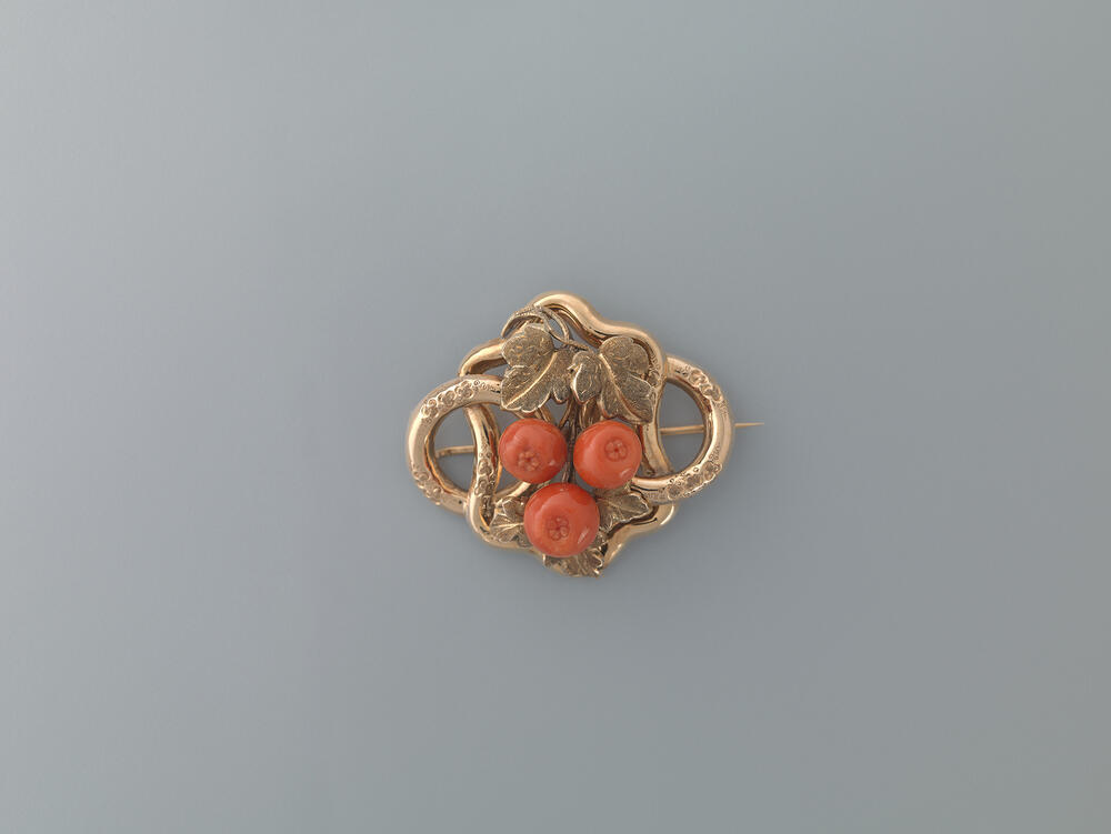 Broche bestaande uit een geslingerde band en koralen in de vorm van granaatappels
