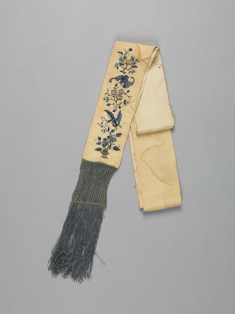 Lange sjerp van crème zijde met geborduurd blauw bloemmotief aan de einden met blauwe macramé franje