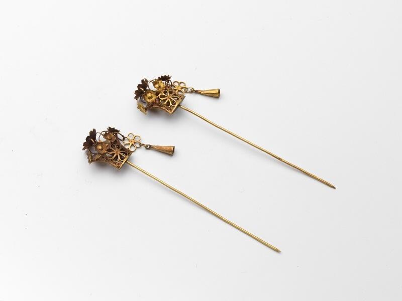 Paar gouden mutsenspelden met knoppen met bloemen, waaraan hanger