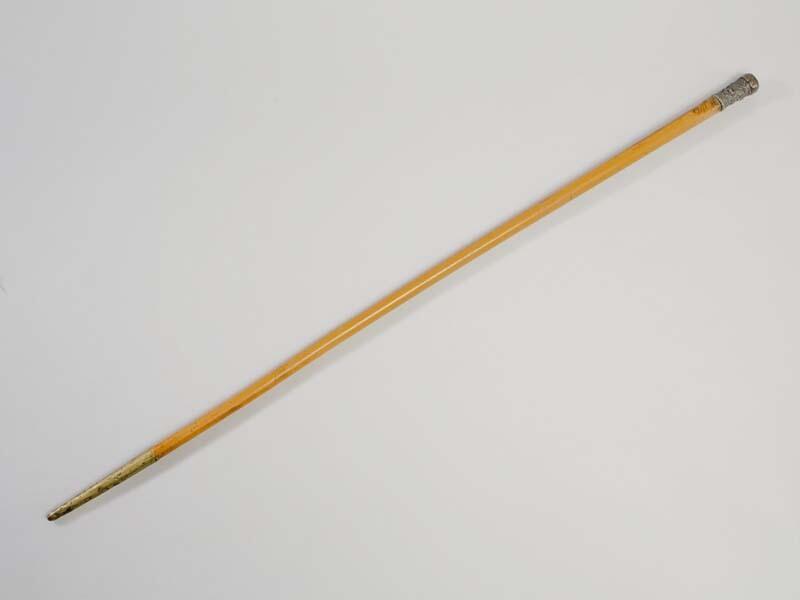 Wandelstok met op het eind een zilveren knop versierd met bloemwerk. Op het ondereind koperen punt