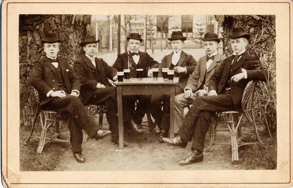 Zes jongemannen rond een tafel, 1900–1920