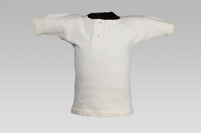 Borstrok genaaid van wit katoenen tricot, met knoopsluiting bij halssplit, onderdeel van groep van…