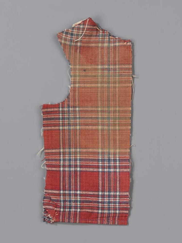Fragment van poppenjakje, rode grond, blauw-wit geruit