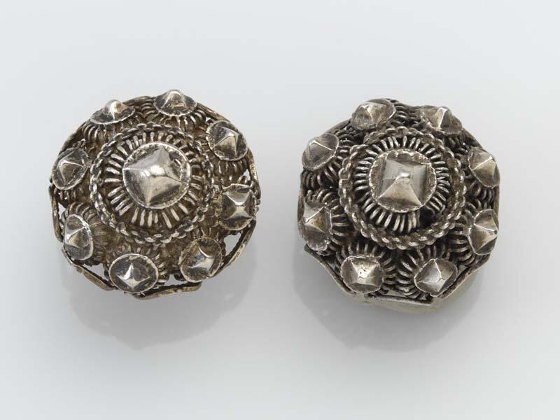 Twee ronde knopen met een kegelvormige bovenkant versierd met een rand van acht diamantkoppen,…