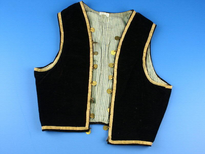 Zwartfluwelen vestje afgezet met goudkleurig band, met aangenaaide muntjes