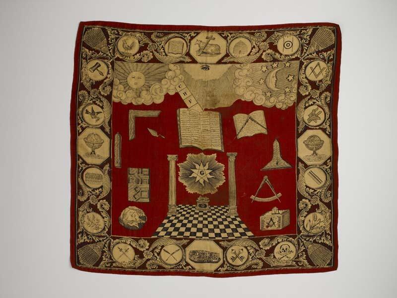 Gedenkdoek van zije met rood fond en zwart-witte tekening met symbolen van de Vrijmetselarij