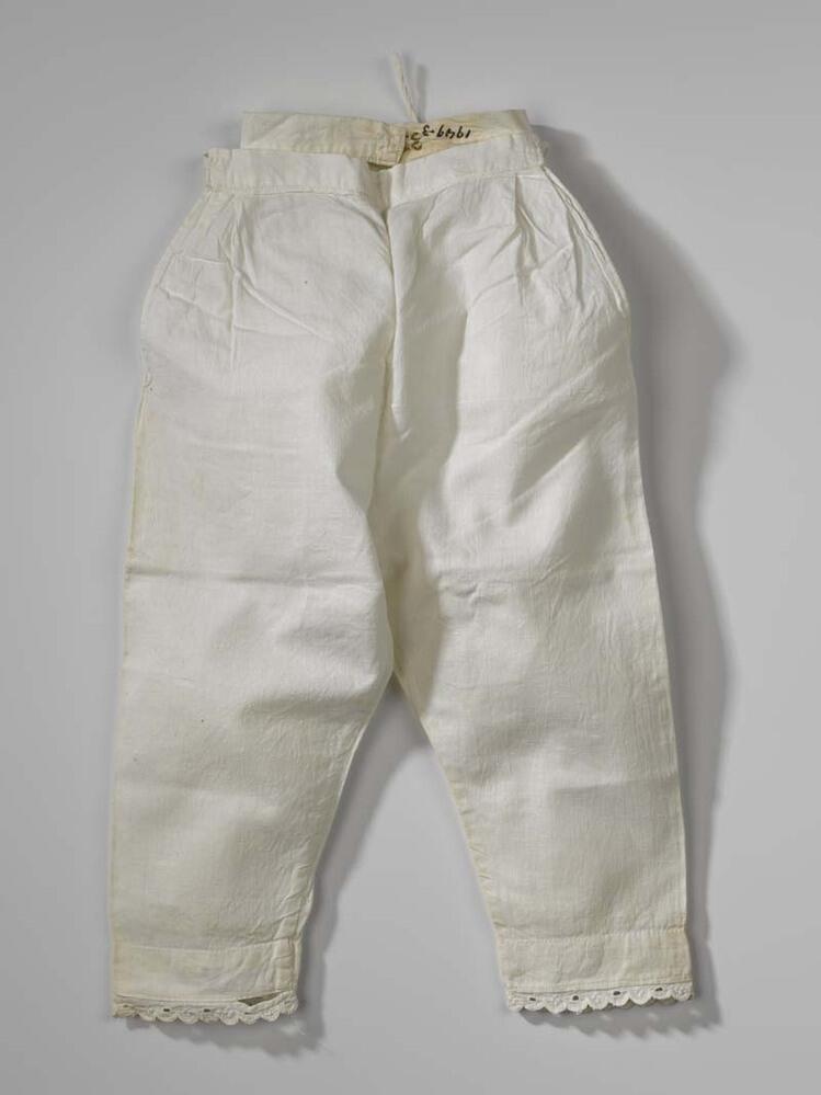 Wit katoenen broek, pijpen met kantje, behorend bij stel poppen- of kinderkleding