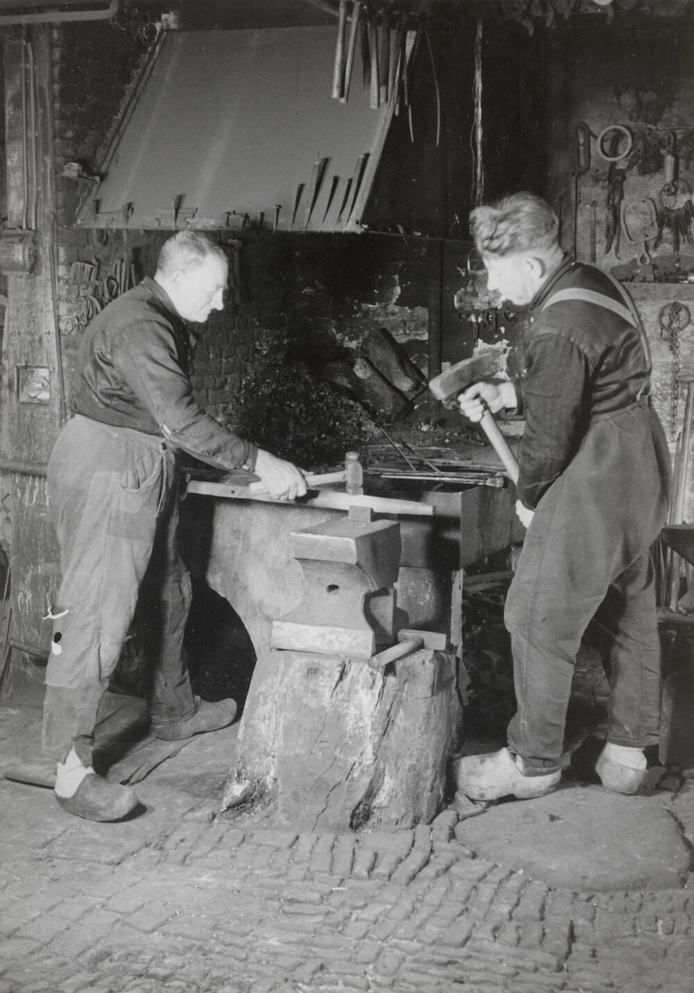 Vader en zoon Kooiker in de smederij, Rouveen, 1944