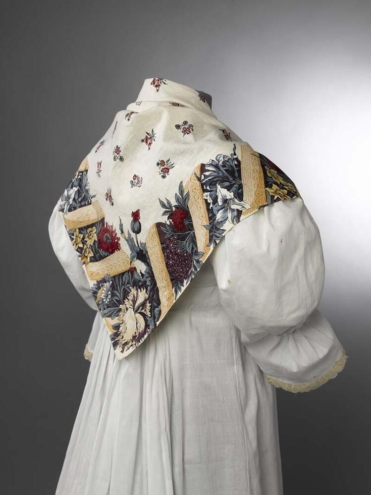 Witte driekante katoenen doek bedrukt met brede rand van een met een lint omwonden bloemslinger en…