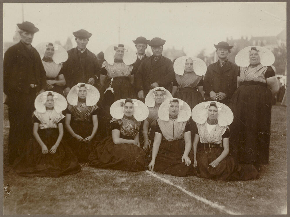 Groep vrouwen, meisjes en mannen in protestantse Zuid-Bevelandse streekdracht, 1913