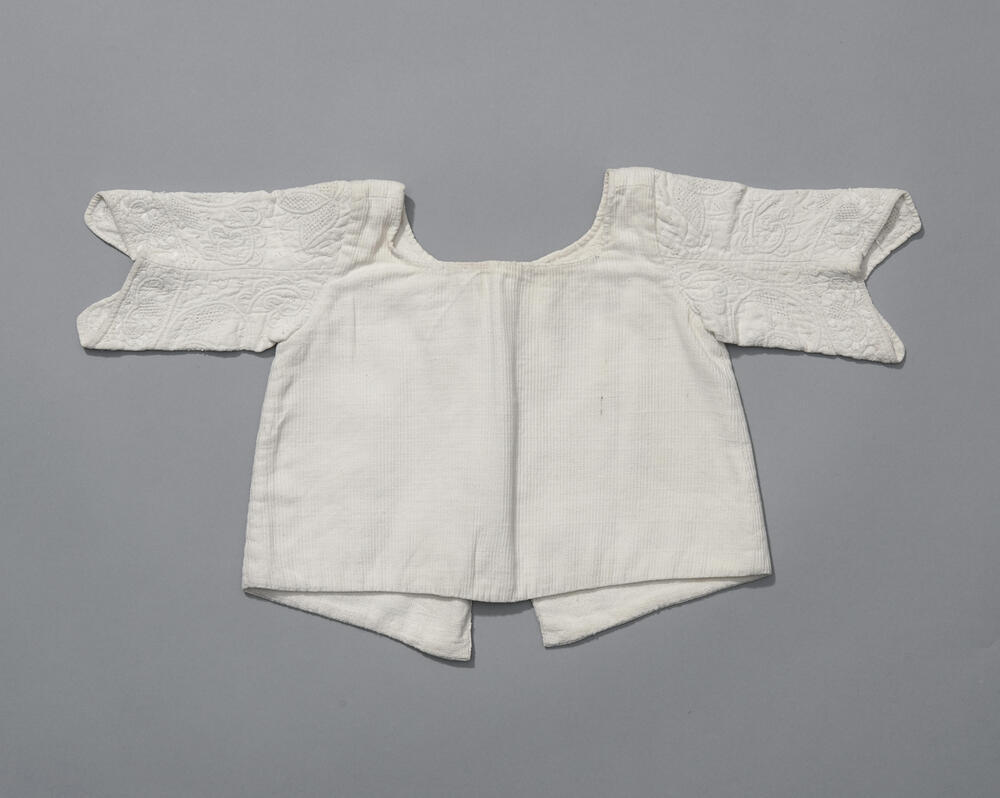Linnen babyjak met mouwen in Zaans stikwerk, voor 1958