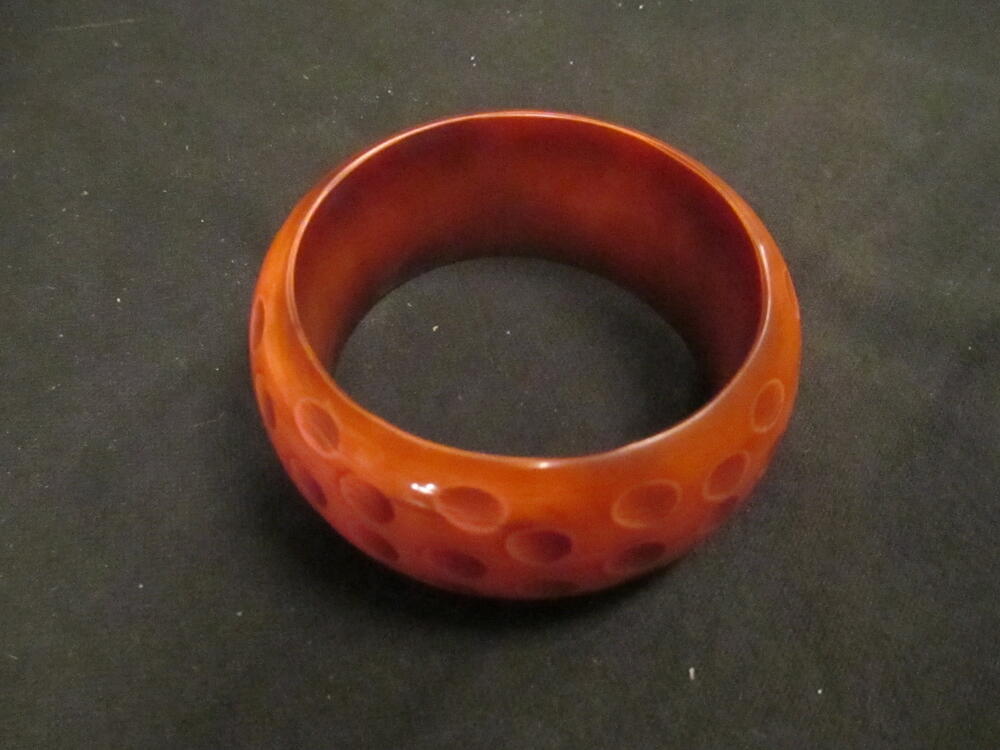 Armband, type 'bangle', van roze/bruin plastic met uitgediepte 'vlekken'