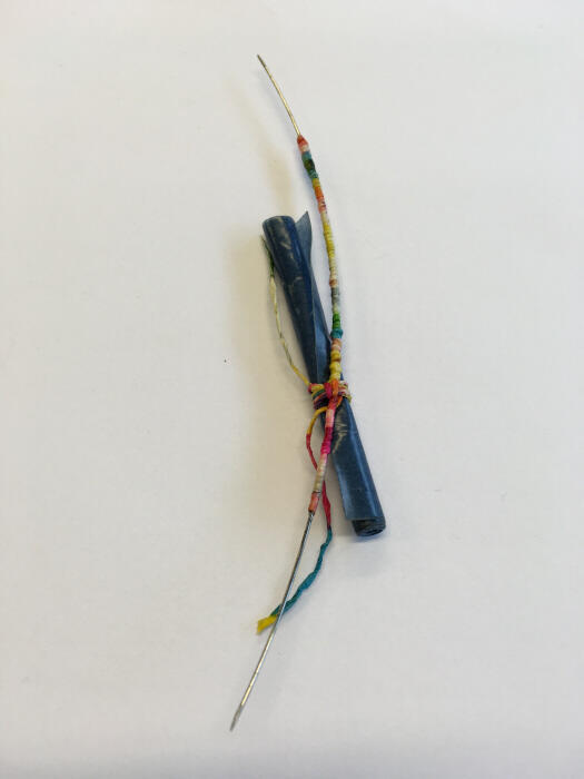 Broche met rolletje blauw papier en omwikkeld staaldraad