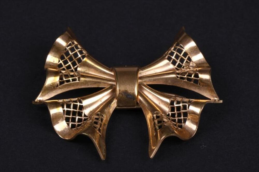 Broche in strikvorm in koperkleurig metaal