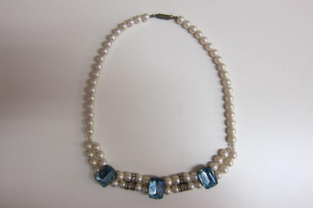 Halsketting in witte plastic parels met blauwe fantasiestenen