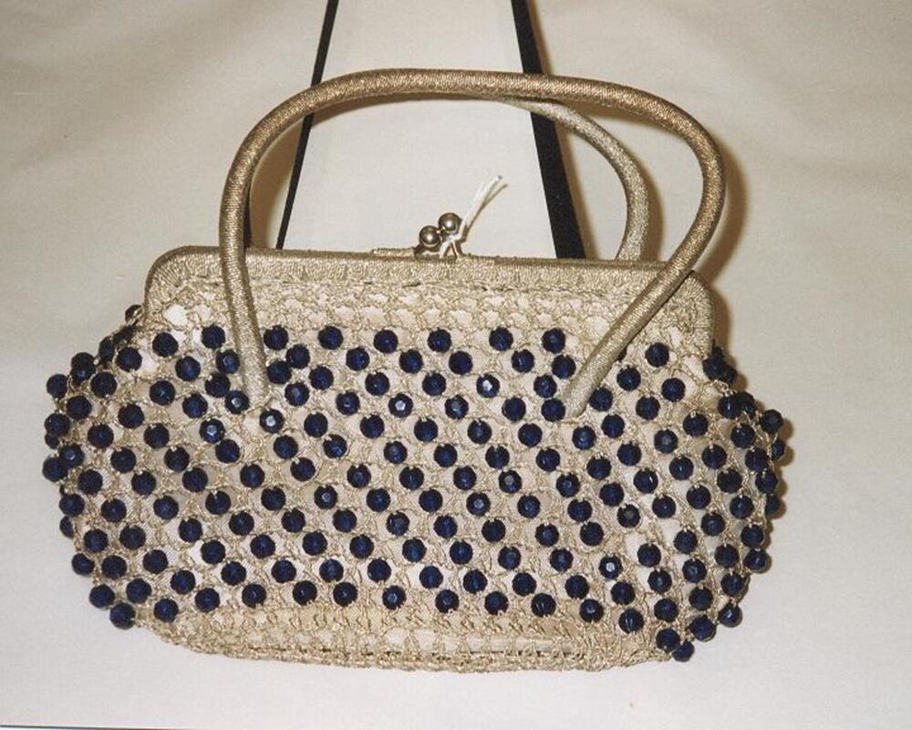 Zilverkleurige handtas met blauwe kralen.