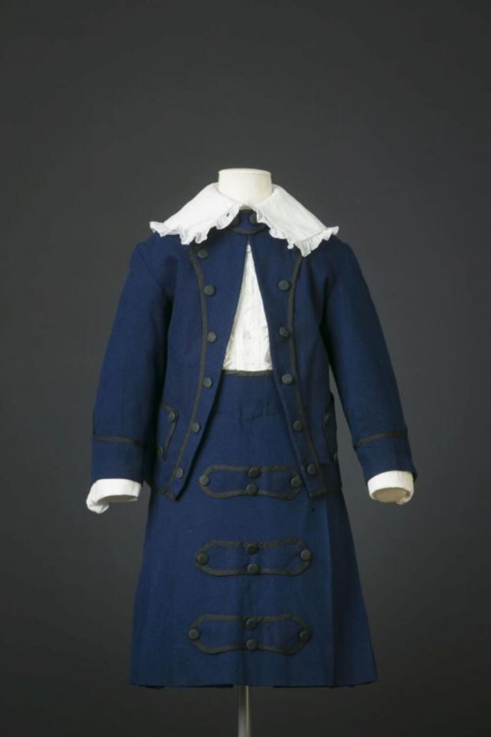 Donkerblauw jongensensemble bestaande uit jasje, rok en witte blouse
