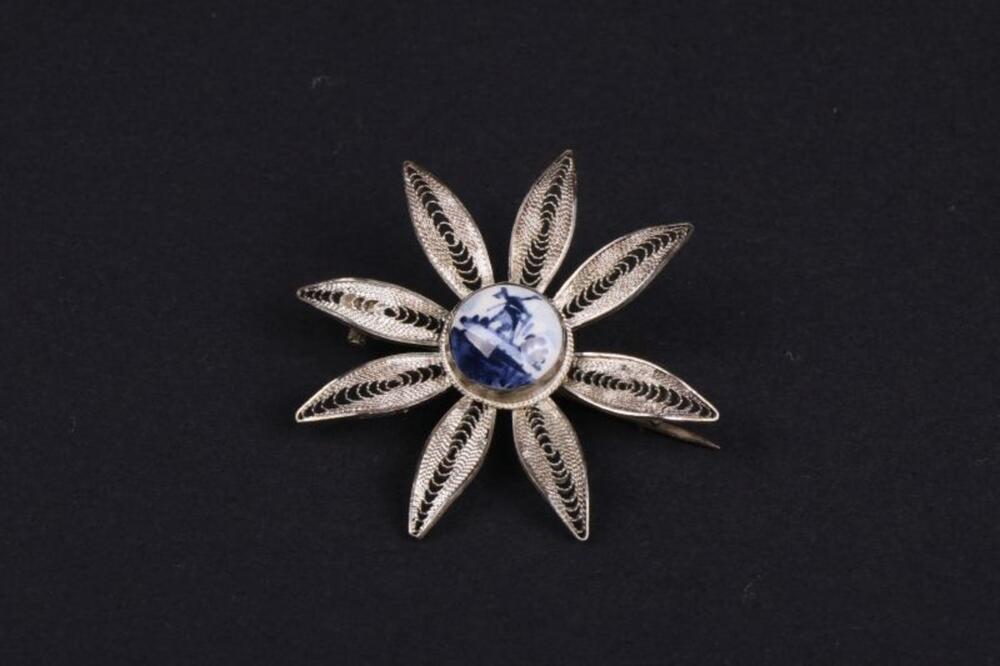 Bloemvormige broche in filigraan zilver met Hollands tafereel in Delfts