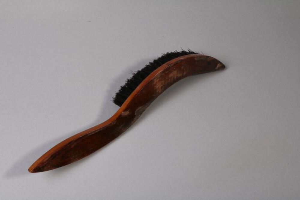 Gekromde hoedenborstel met houten handvat en zwarte stugge haren