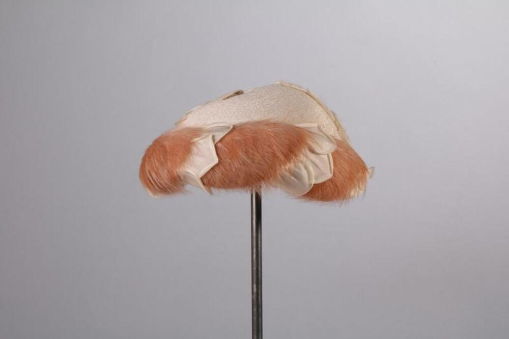Schelpvormige cocktailhoed in crèmekleurige lurex met veertjes