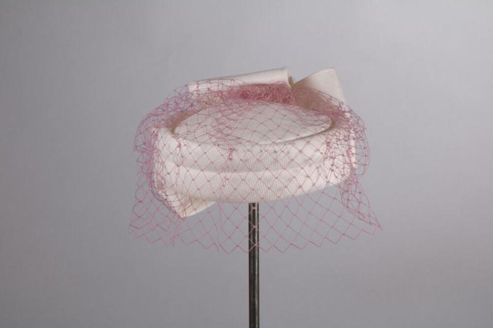 Hoed in witte synthetische raffia met grote witte strik en roze voile