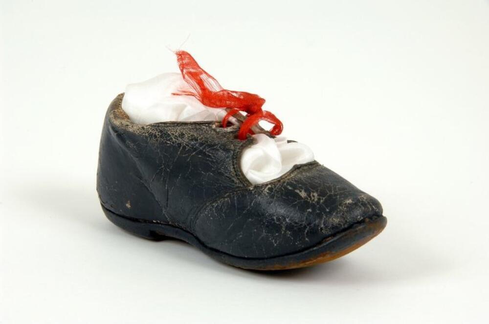 Kinderschoen in zwart leer versierd met rood lint