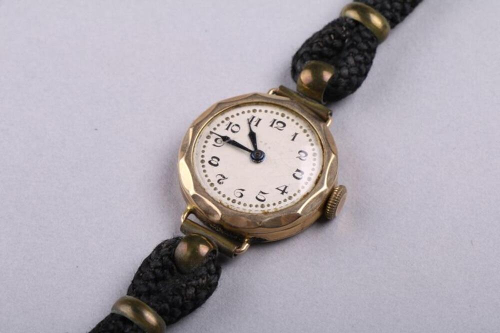 Rond, klein, goudkleurig, metalen uurwerk met polsbandje in leer en koord