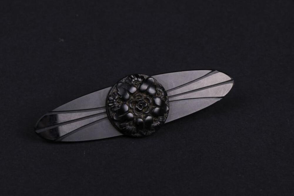 Twee zwarte ovale broches met een uitgewerkte rosas