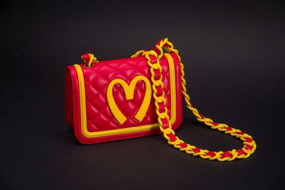 Ensemble bestaande uit rood leren handtas met gele logo van 'Mc Donald' en bijhorende zak