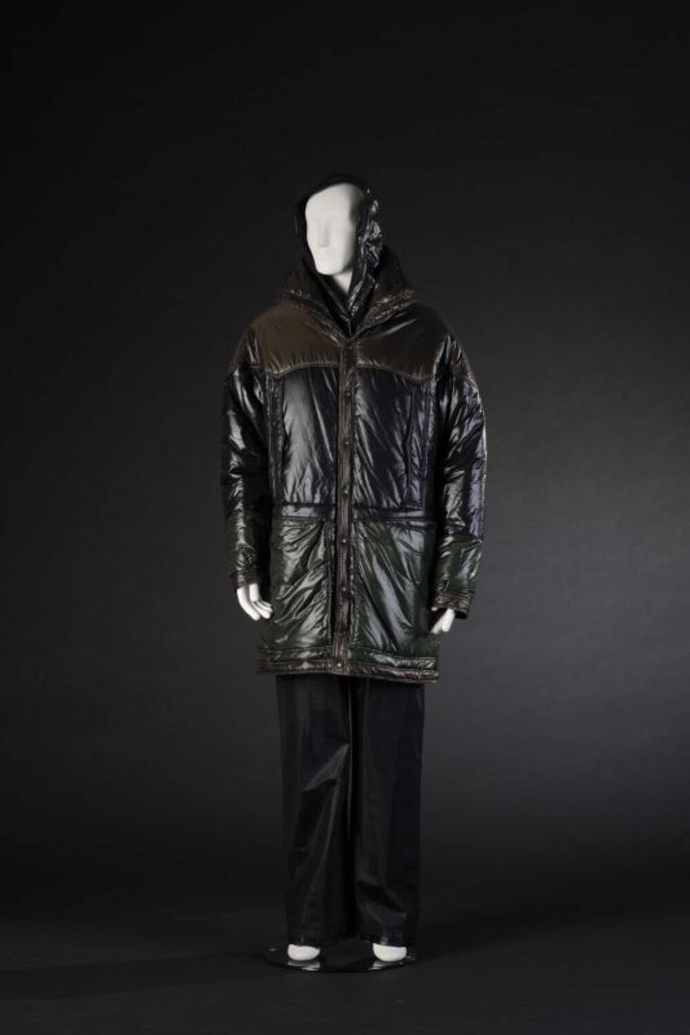 Ensemble bestaande uit gewatteerde parka in groen-bruin-zwarte, glanzende stof, zwarte, leren broek…
