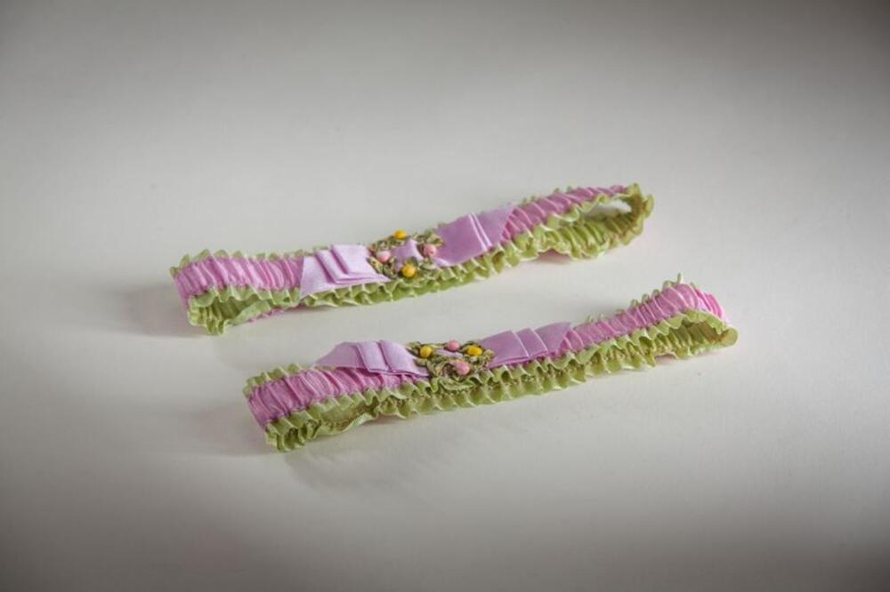 Pastelroze en -groene kousenband met bloemenversiering