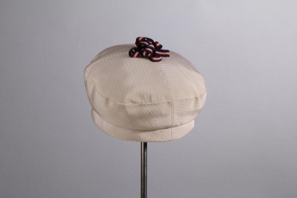 Bonnet in witte ripssatijn met rozet van cordonnet-lint