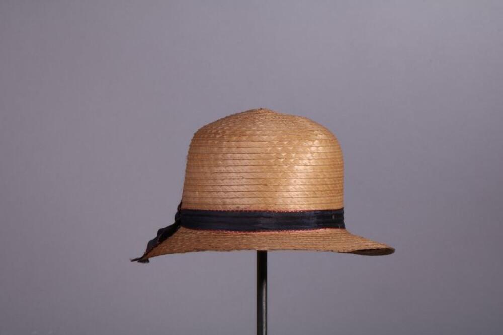 Hoed in naturel stro versierd met blauw-rood lint