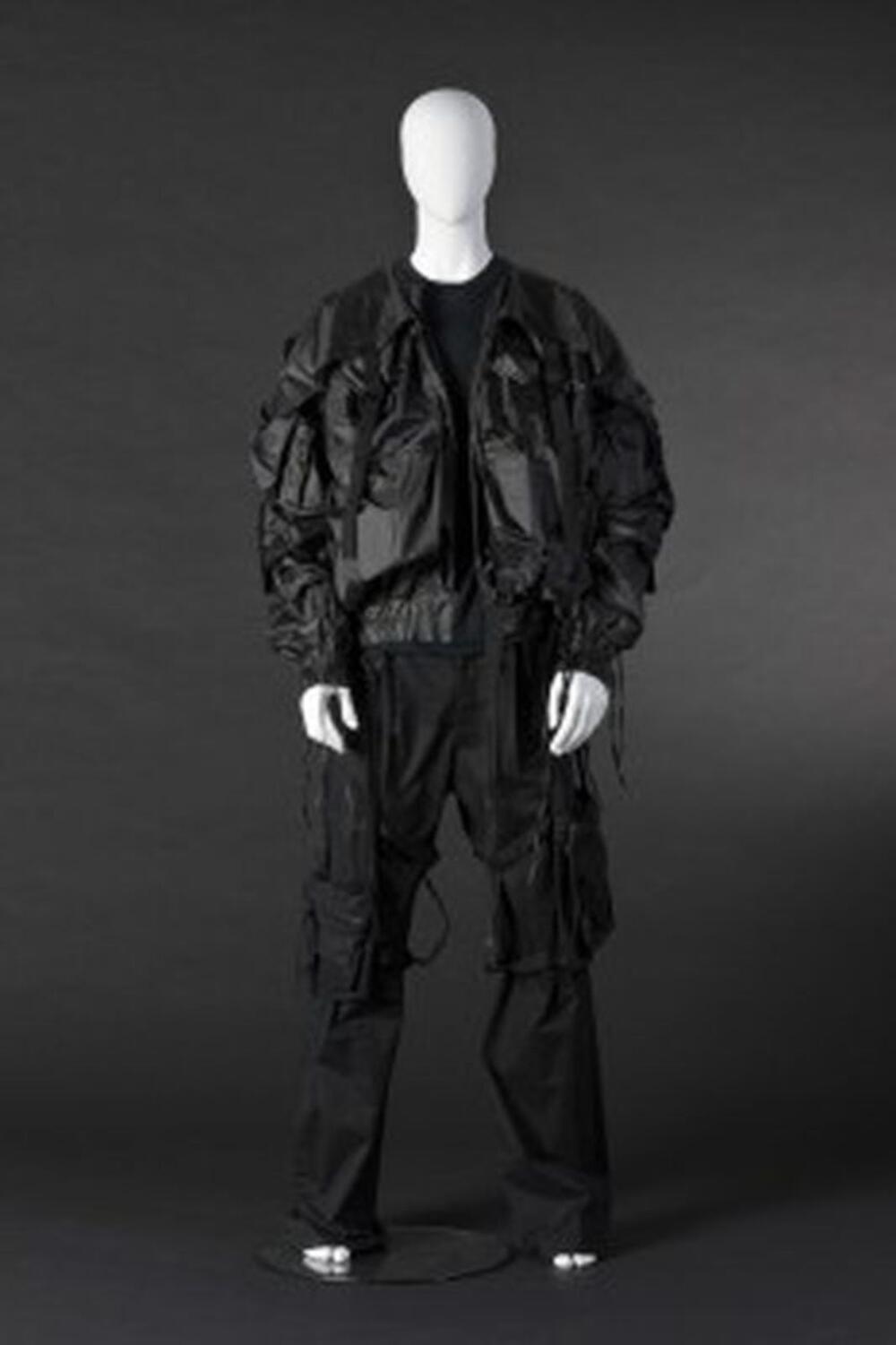 Ensemble bestaande uit zwarte broek, riem, T-shirt en vest in blousonmodel