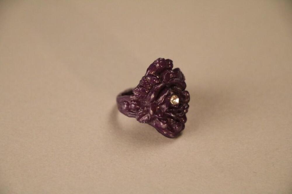 Ring in donkerblauw plastic in vorm van bloem versierd met stras