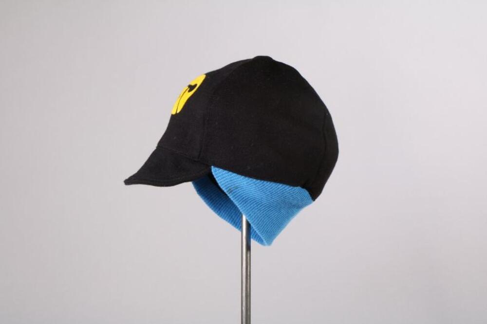 Pet in zwarte tricot met blauwe boord en geel logo