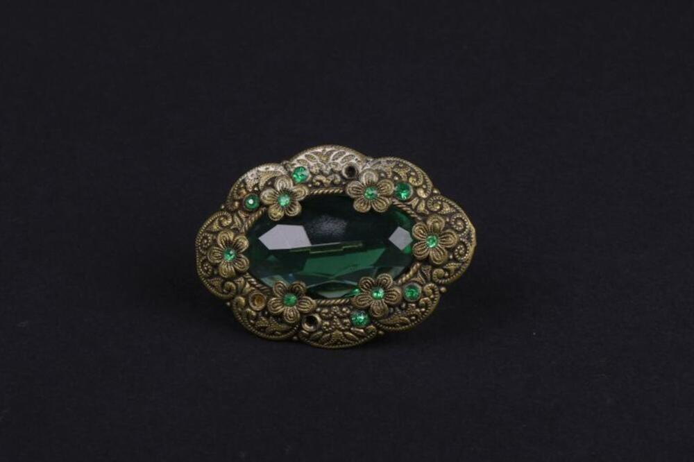 Broche in groen geslepen glas ingelegd in koper