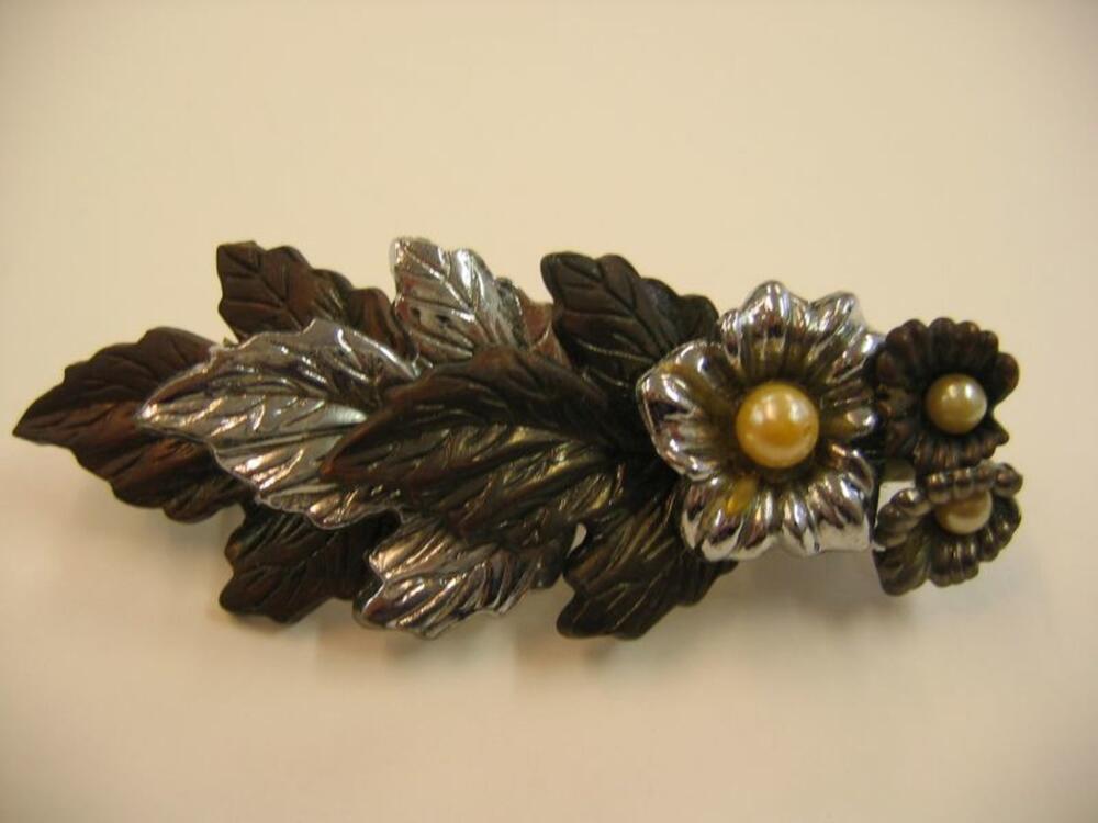 Grote, zilver- en bronskleurige haarspeld met blad- en bloemmotief