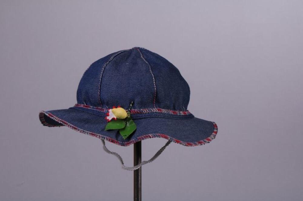 Zomerhoed in blauwe denim met gekleurde stiksels en bloem