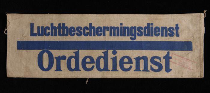 Mouwband, wit keperkatoen met opdruk in donkerblauw, "Luchtbeschermingsdienst Ordedienst", rode…