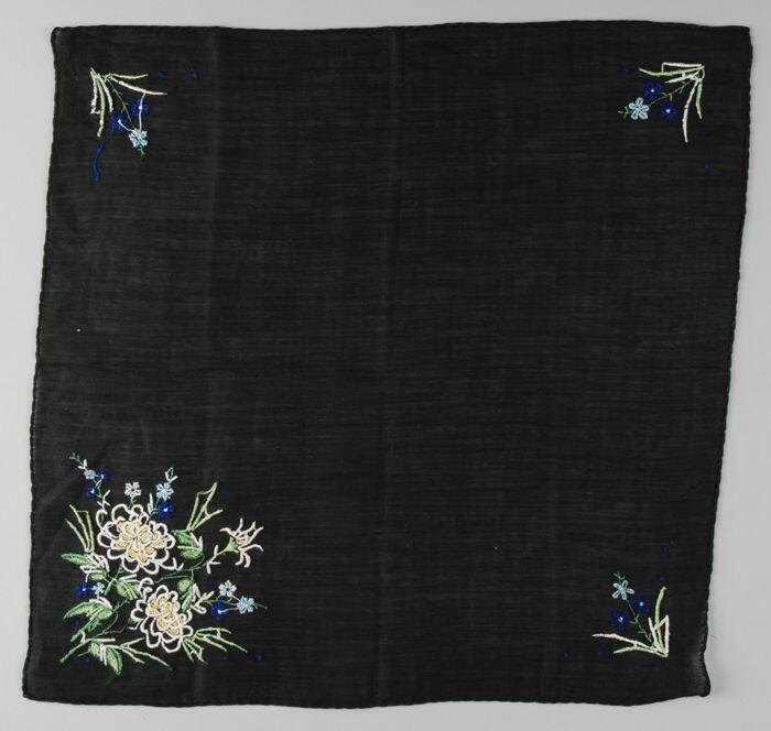 Vierkante zwart katoenen zakdoek met borduursel in groen, blauw en wit, op drie hoeken kleine bloem…
