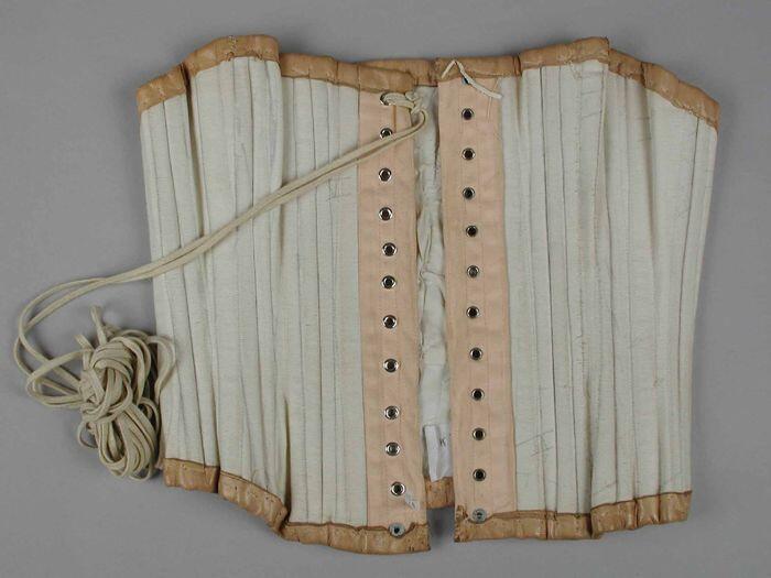 Korset van wit katoen verstevigd met baleinen, vetersluiting, afgebiesd met zacht beige leer, witte…