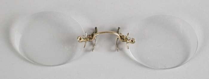 Knijpbril of pince-nez zonder montuur, met ovale glazen op sterkte, goudkleurige brug en flexibele…