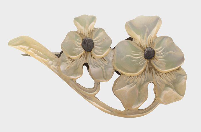 Broche van uit parelmoer gestoken kaapse viooltjes, op een messing speld