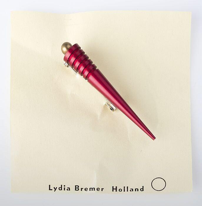 Kegelvormige broche van rood aluminium, met aan basis kegel messing knop